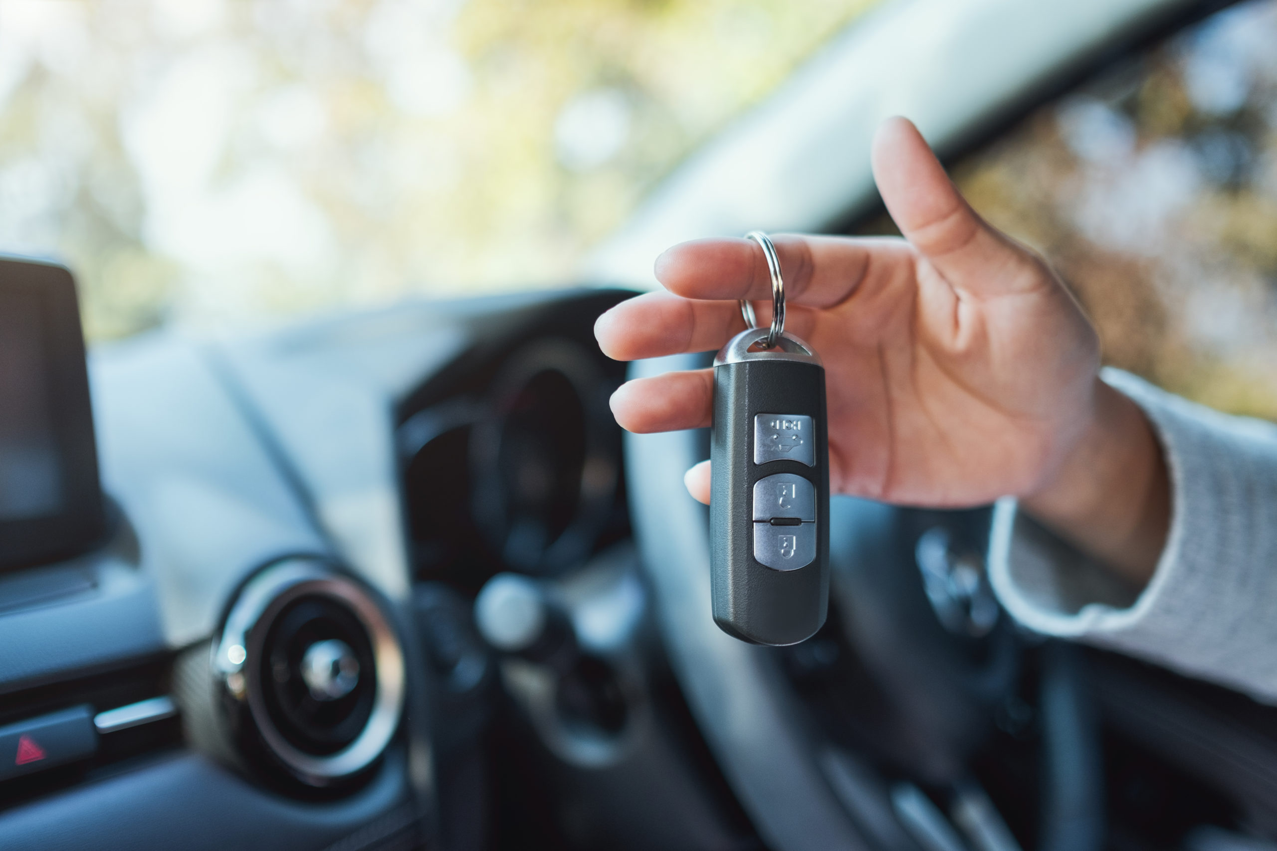 A woman holding and showing car key while sitting in the car