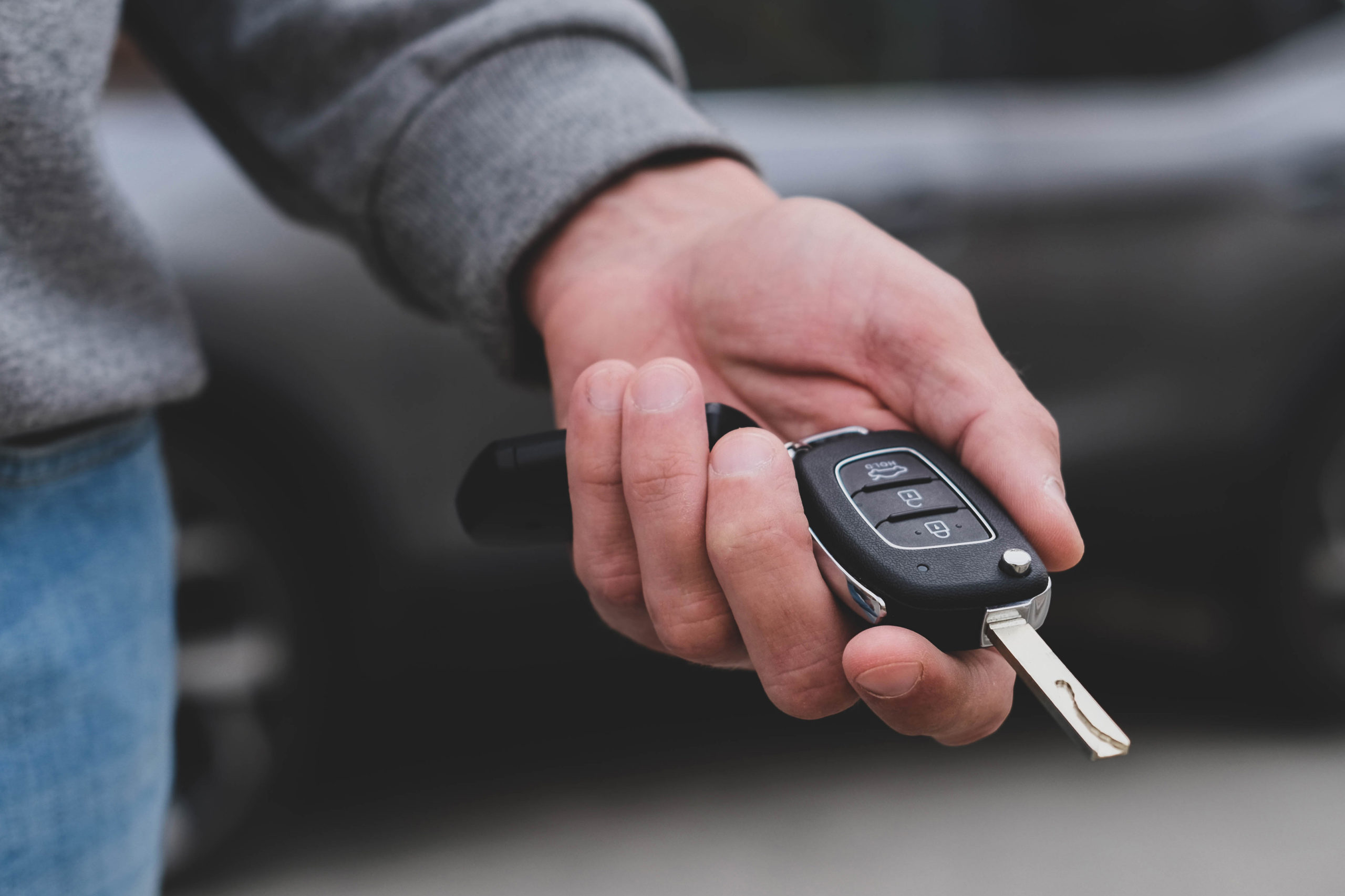 Man in front of the new car and holding keys. Salesman is carryi